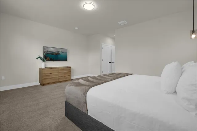 a bedroom with a large bed flat screen tv and window