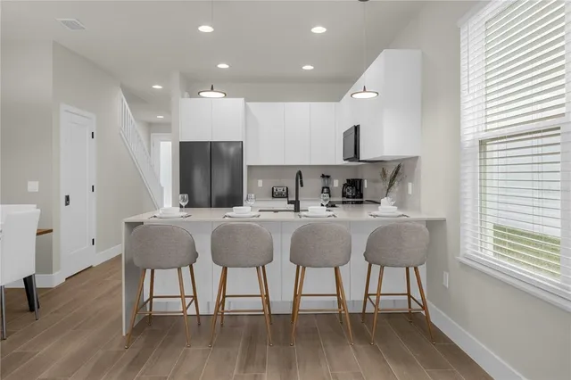 a kitchen with stainless steel appliances granite countertop a table chairs sink and cabinets