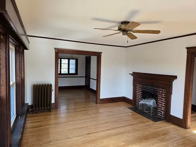 a view of an empty room with wooden floor and a fireplace