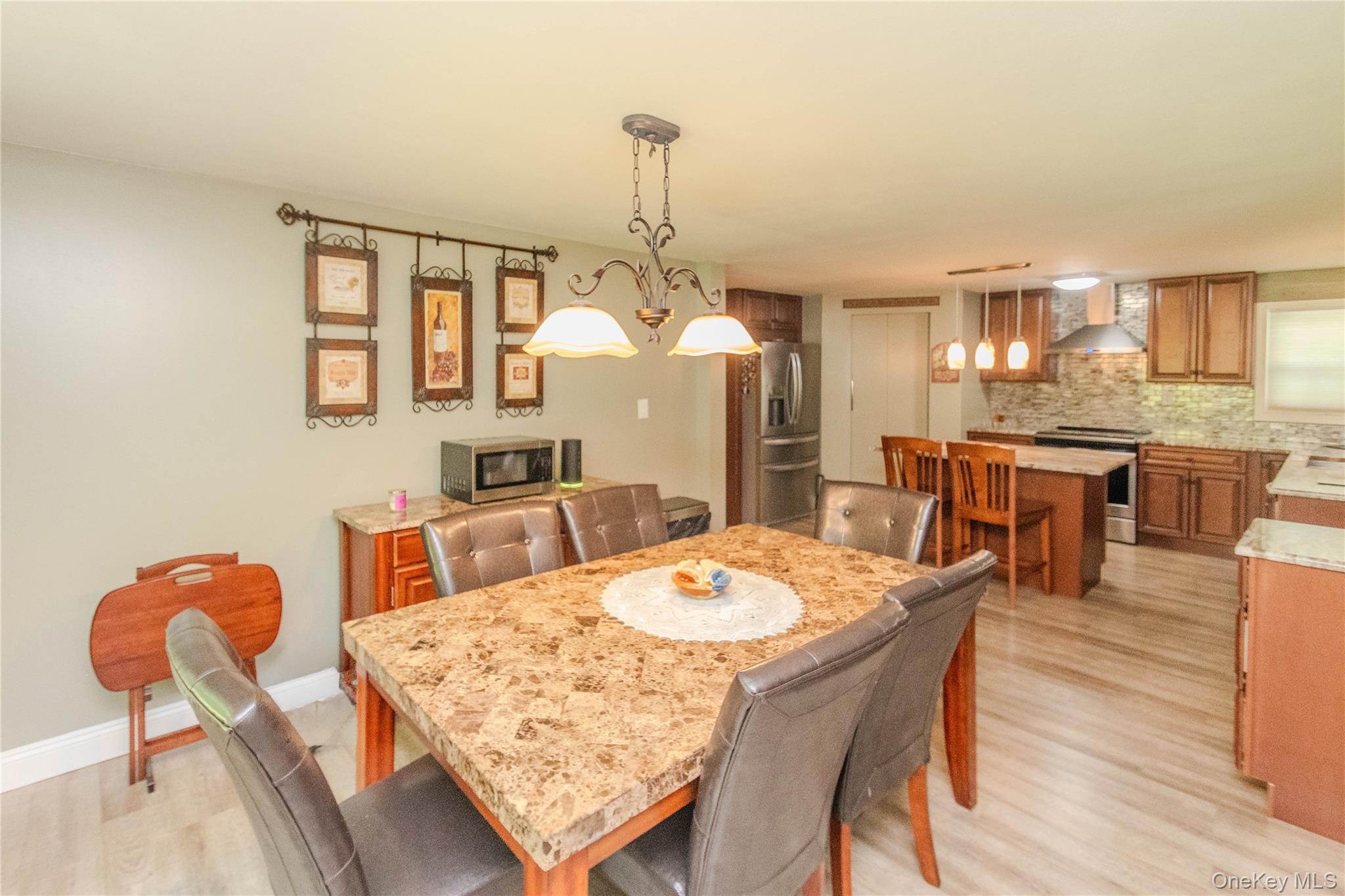 15 Van Dewark Road Middletown, NY 10941 - Photo 13 of 41 Open-concept dining area featuring a stone-look tabletop, wrought iron chandelier, and wood-finish flooring