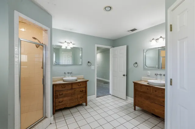 a bathroom with a double vanity sink mirror and shower