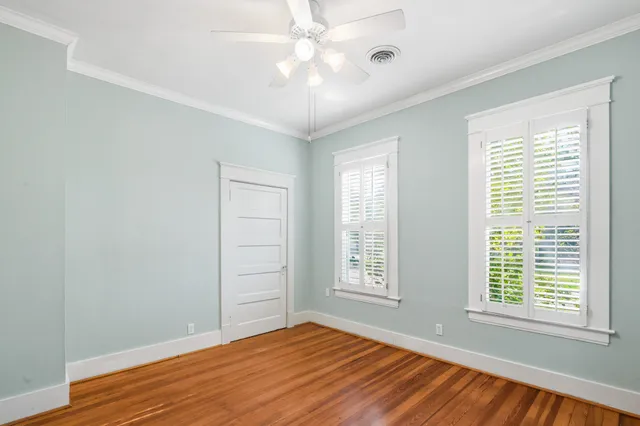 a view of empty room with wooden floor and fan