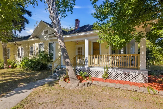 a view of a brick house with large windows and a small yard