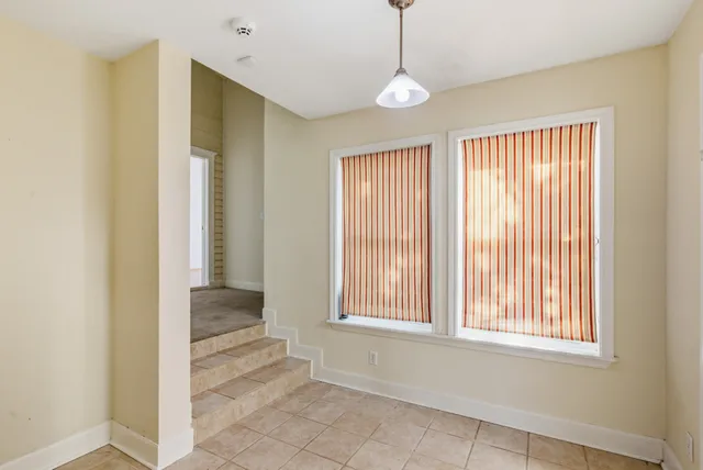a view of an empty room with window and chandelier fan