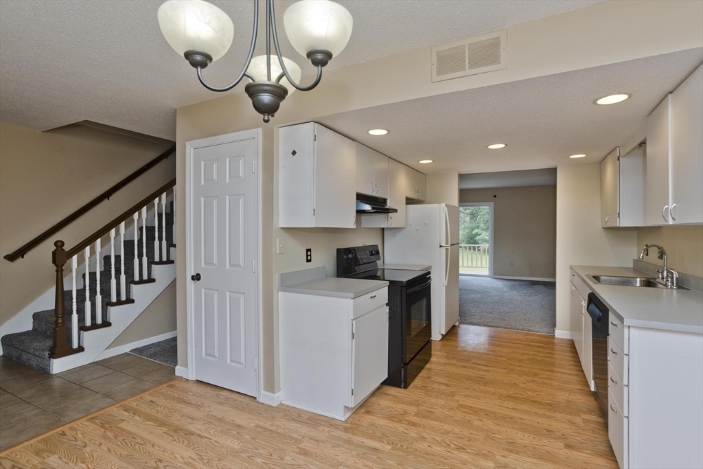 610 County Road, Unit 7 Holyoke, MA 01040 - Photo 9 of 24 a kitchen with stainless steel appliances granite countertop a sink a stove top oven a chimney wooden floor and cabinets
