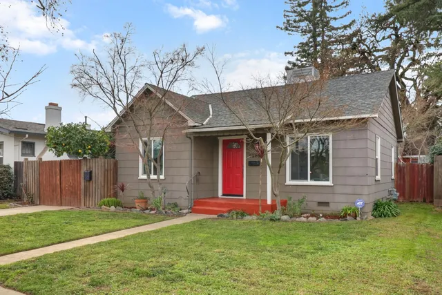 a view of a house with large tree and wooden fence