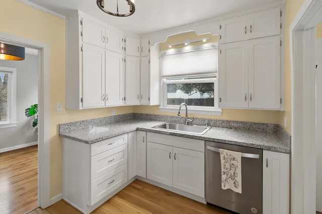 a view of a kitchen with a sink dishwasher wooden floor and a fireplace