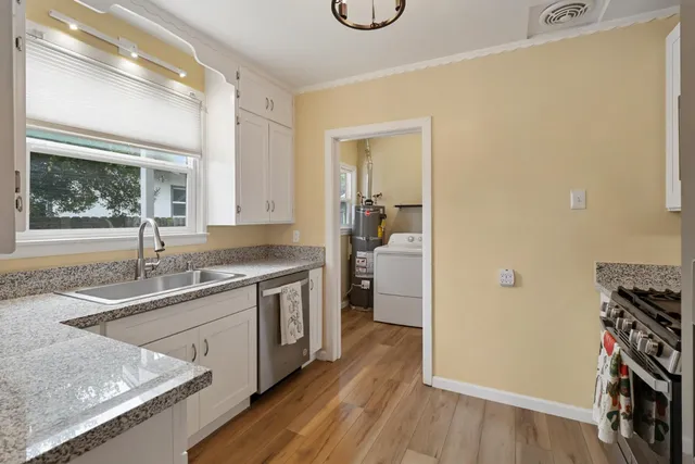 a kitchen with stainless steel appliances white cabinets a stove a sink and a refrigerator