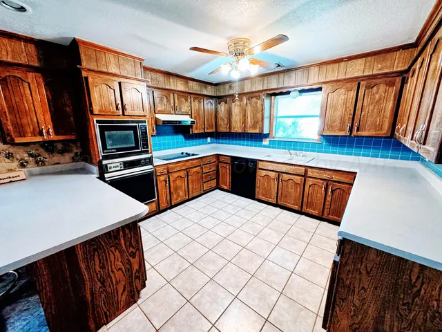 a kitchen with stainless steel appliances a sink a stove a refrigerator cabinets and a dining table