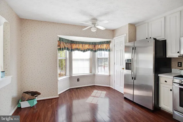 a kitchen with white cabinets stainless steel appliances and wooden floor