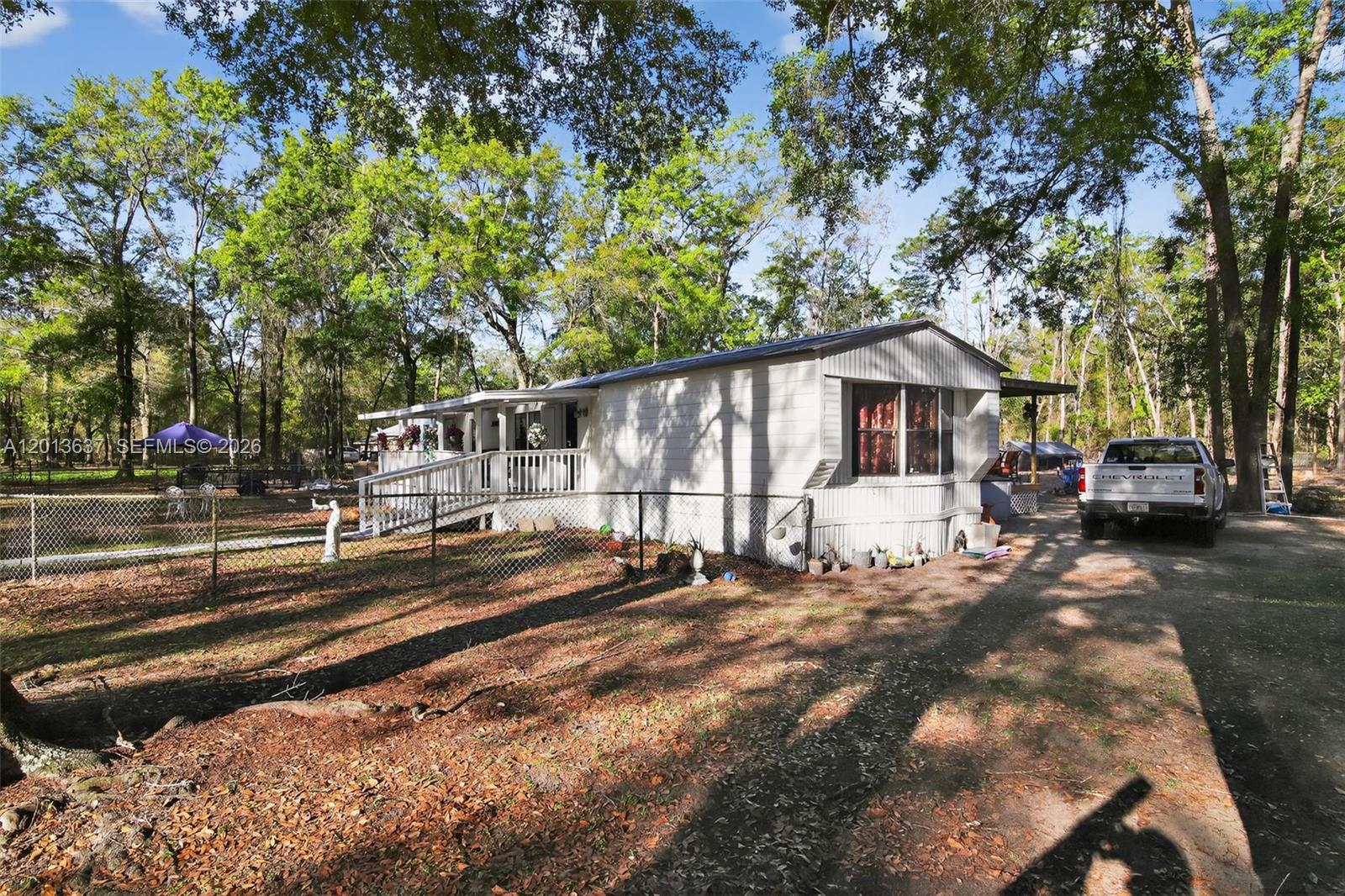 2522 Northwest 121st Avenue Gainesville, FL 32609 - Photo 10 of 40 a view of a white house with a large tree and lawn chairs
