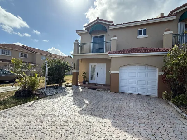 a front view of a house with a yard and potted plants