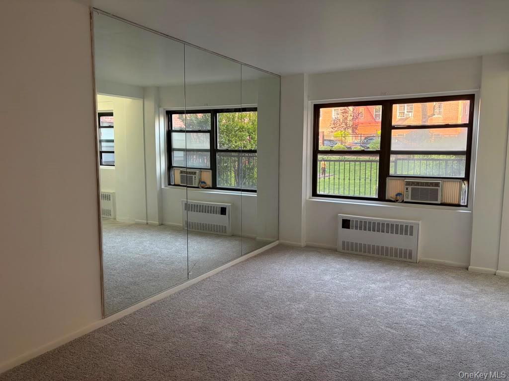 99-60 63rd Road, Unit 1H Queens, NY 11374 - Photo 2 of 11 an empty room with a fireplace and windows