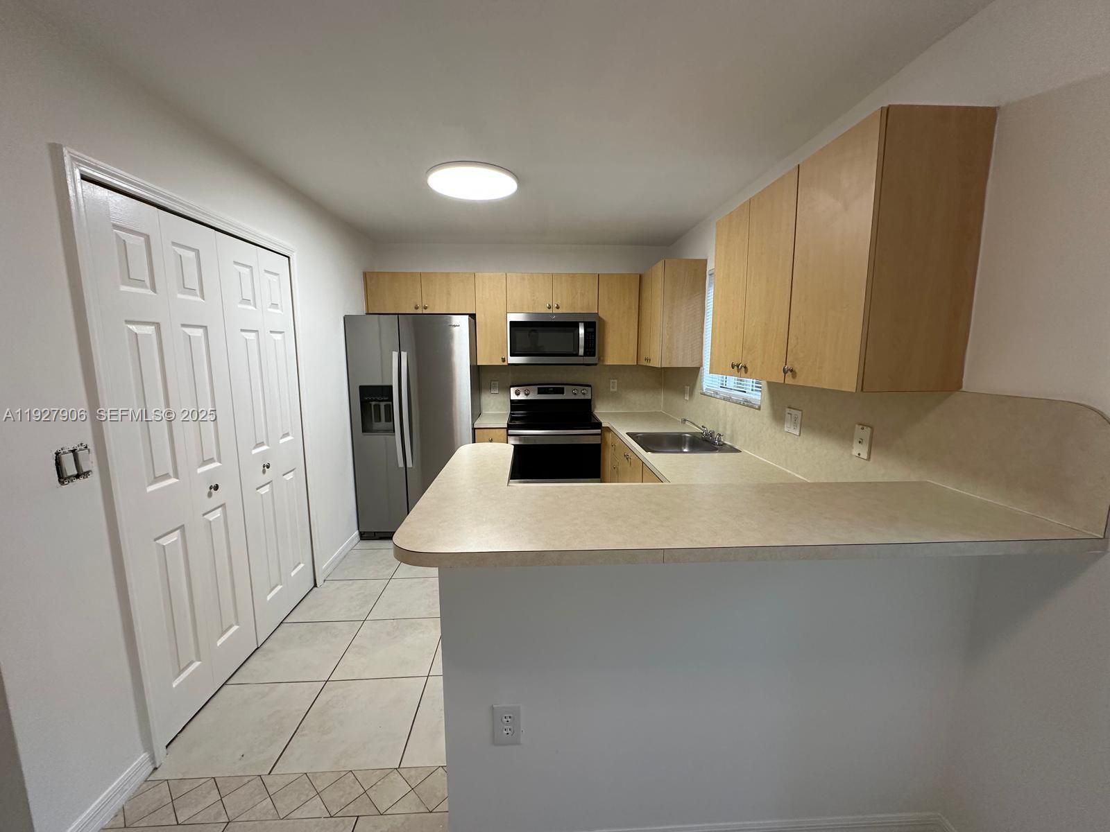 2911 Southeast 13th Road, Unit 10140 Homestead, FL 33035 - Photo 5 of 22 a kitchen with a sink and a refrigerator