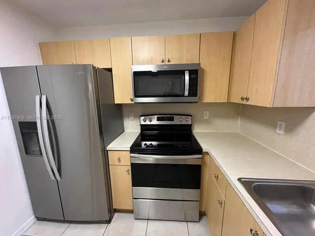 a kitchen with granite countertop white cabinets sink and stainless steel appliances