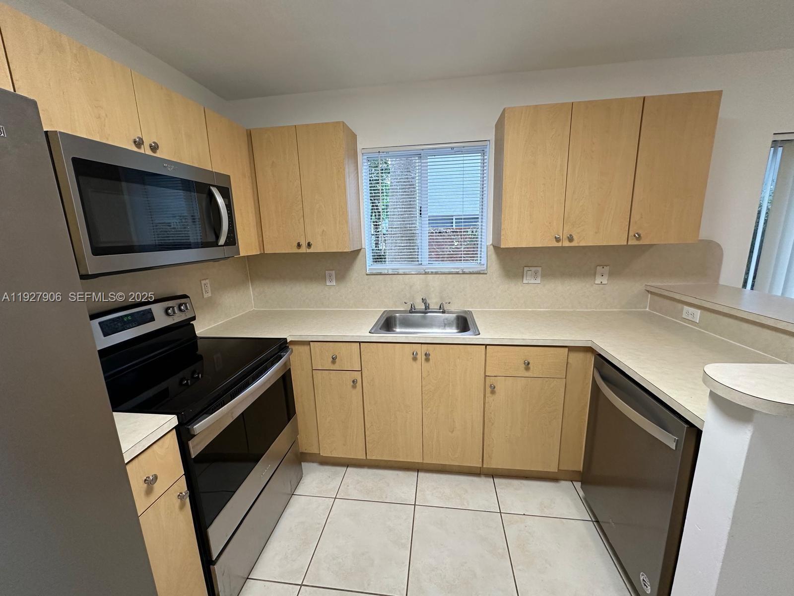 2911 Southeast 13th Road, Unit 10140 Homestead, FL 33035 - Photo 8 of 22 a kitchen with granite countertop white cabinets sink and stainless steel appliances