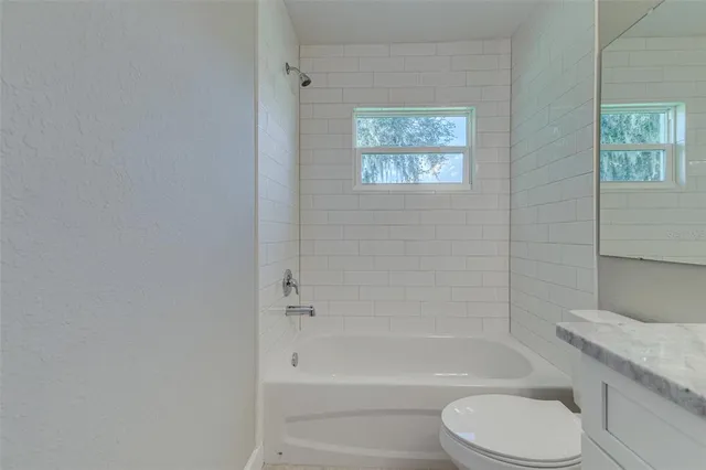 a bathroom with a granite countertop toilet a sink and bathtub