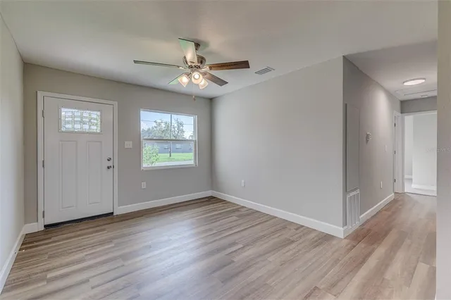 a view of an empty room with wooden floor and a window