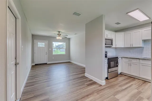a view of kitchen with granite countertop white cabinets and wooden floor