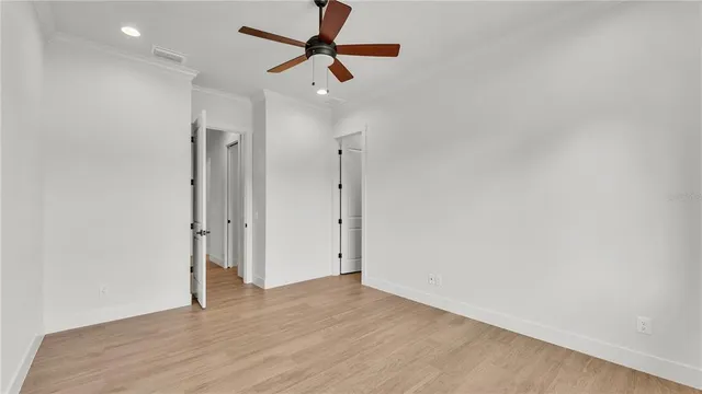 an empty room with wooden floor ceiling fan and windows