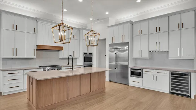 a kitchen with stainless steel appliances granite countertop a sink a stove a refrigerator and cabinets with wooden floor