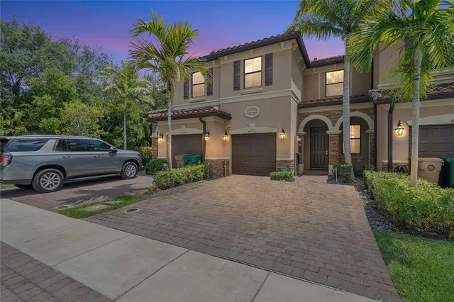 a front view of a house with garage and plants
