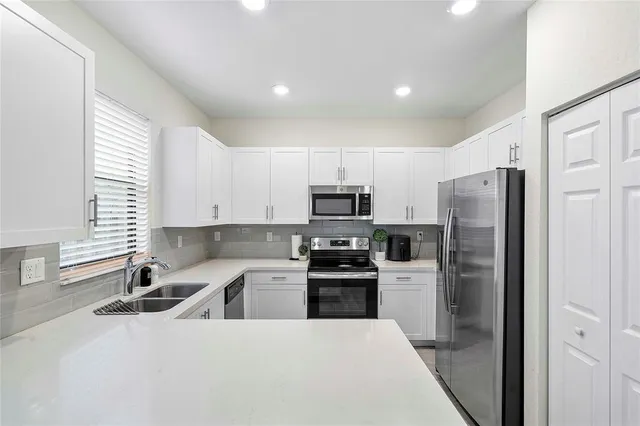 a kitchen with stainless steel appliances a refrigerator sink and white cabinets
