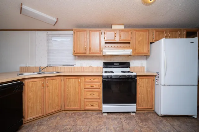 a kitchen with stainless steel appliances granite countertop a refrigerator stove a sink and dishwasher