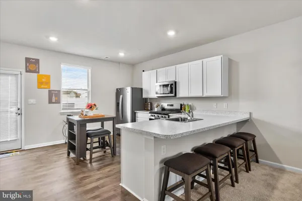 a kitchen with stainless steel appliances a dining table chairs microwave and sink