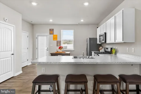 a kitchen with stainless steel appliances granite countertop a table chairs sink and cabinets