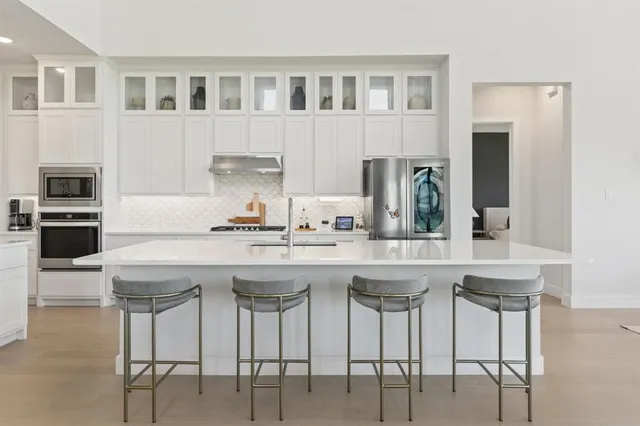 a kitchen with stainless steel appliances granite countertop a white cabinets and chairs