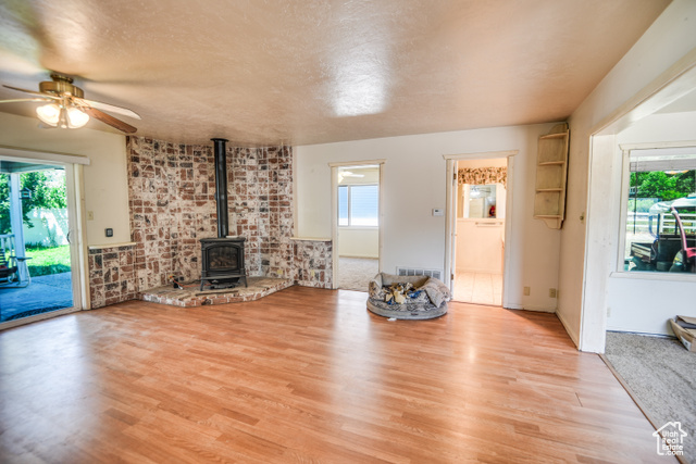 2373 East 190 North Beaver, UT 84713 - Photo 26 of 54 Unfurnished living room with a wood stove, light wood-style floors, ceiling fan, and a textured ceiling