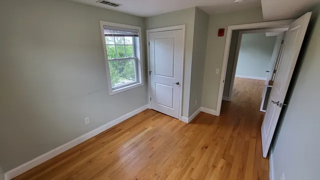 a view of an empty room with wooden floor and a window