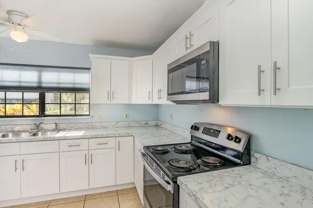 a kitchen with stainless steel appliances granite countertop white cabinets and window