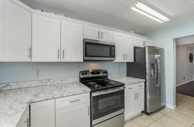 a kitchen with granite countertop white cabinets stainless steel appliances and a sink