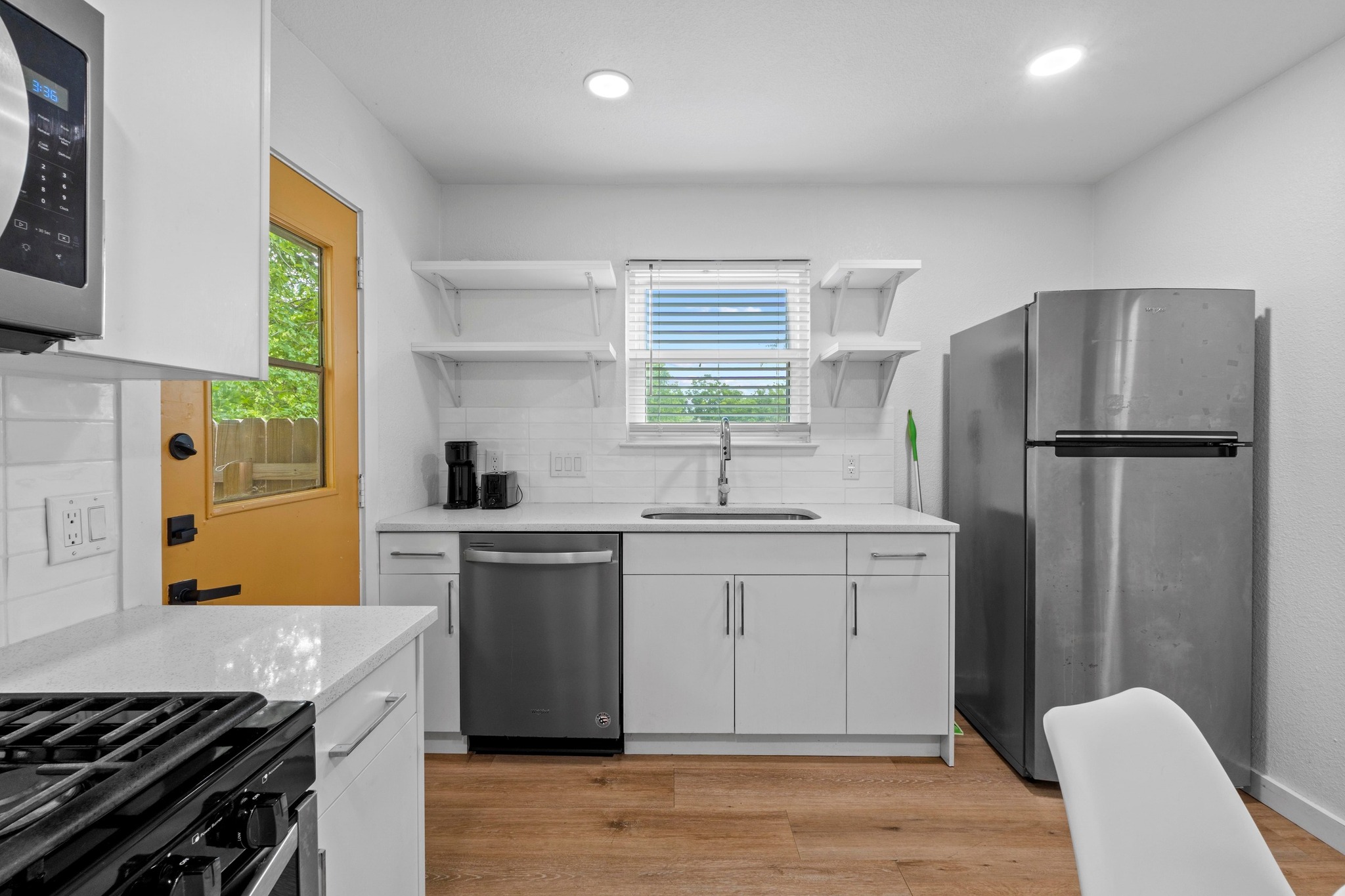 10601 Macmora Road, Unit B Austin, TX 78758 - Photo 11 of 22 A well-lit kitchen with sleek stainless steel appliances, a deep basin sink, and warm wood flooring.
