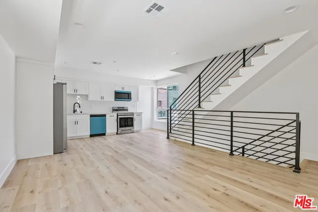 a view of a kitchen with stainless steel appliances wooden floor and a window