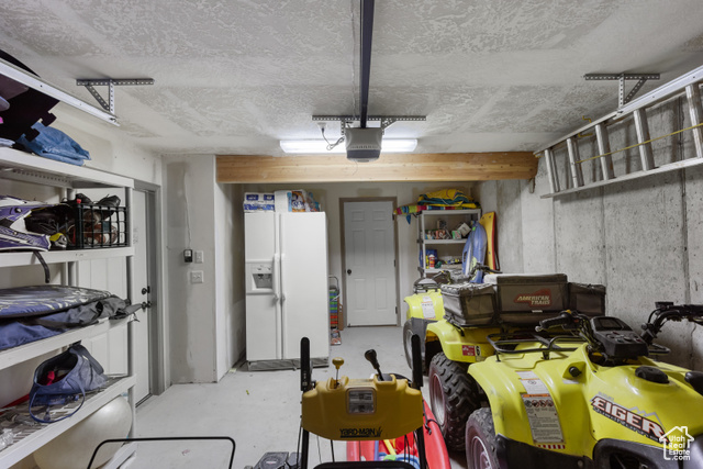 1340 Trapper Loop Garden City, UT 84028 - Photo 28 of 35 Garage with white refrigerator with ice dispenser and a garage door opener