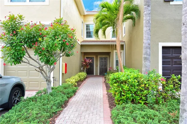 a view of a house with potted plants and a large tree