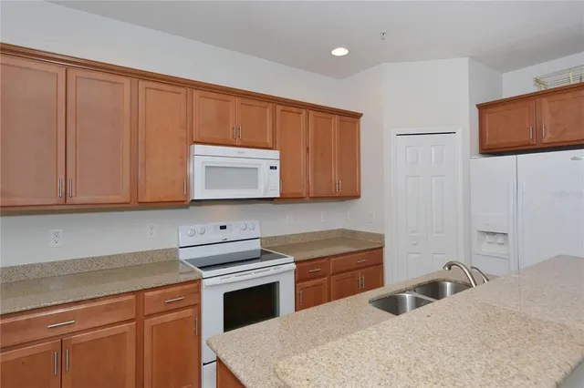 a kitchen with granite countertop a sink a stove and a microwave oven in a white cabinets
