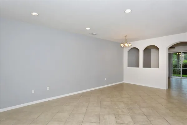 an empty room with chandelier fan and glass door
