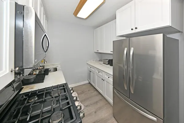 a kitchen with stainless steel appliances granite countertop a refrigerator and white cabinets