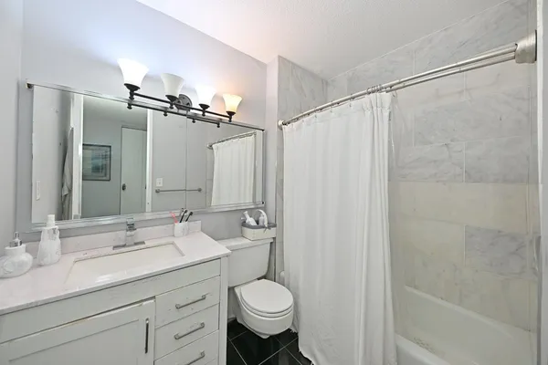 a bathroom with a granite countertop sink toilet and shower