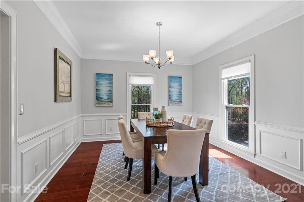 8866 Collins Road Indian Land, SC 29707 - Photo 11 of 48 a dining room with wooden floor a chandelier a wooden table and chairs