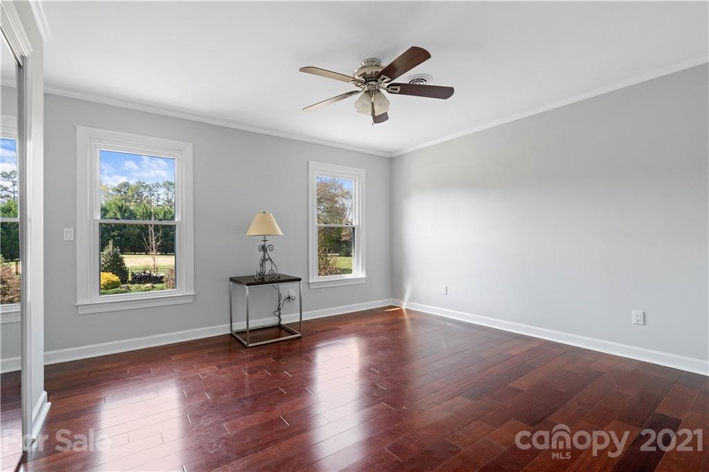 8866 Collins Road Indian Land, SC 29707 - Photo 28 of 48 a view of an empty room with window wooden floor and a ceiling fan