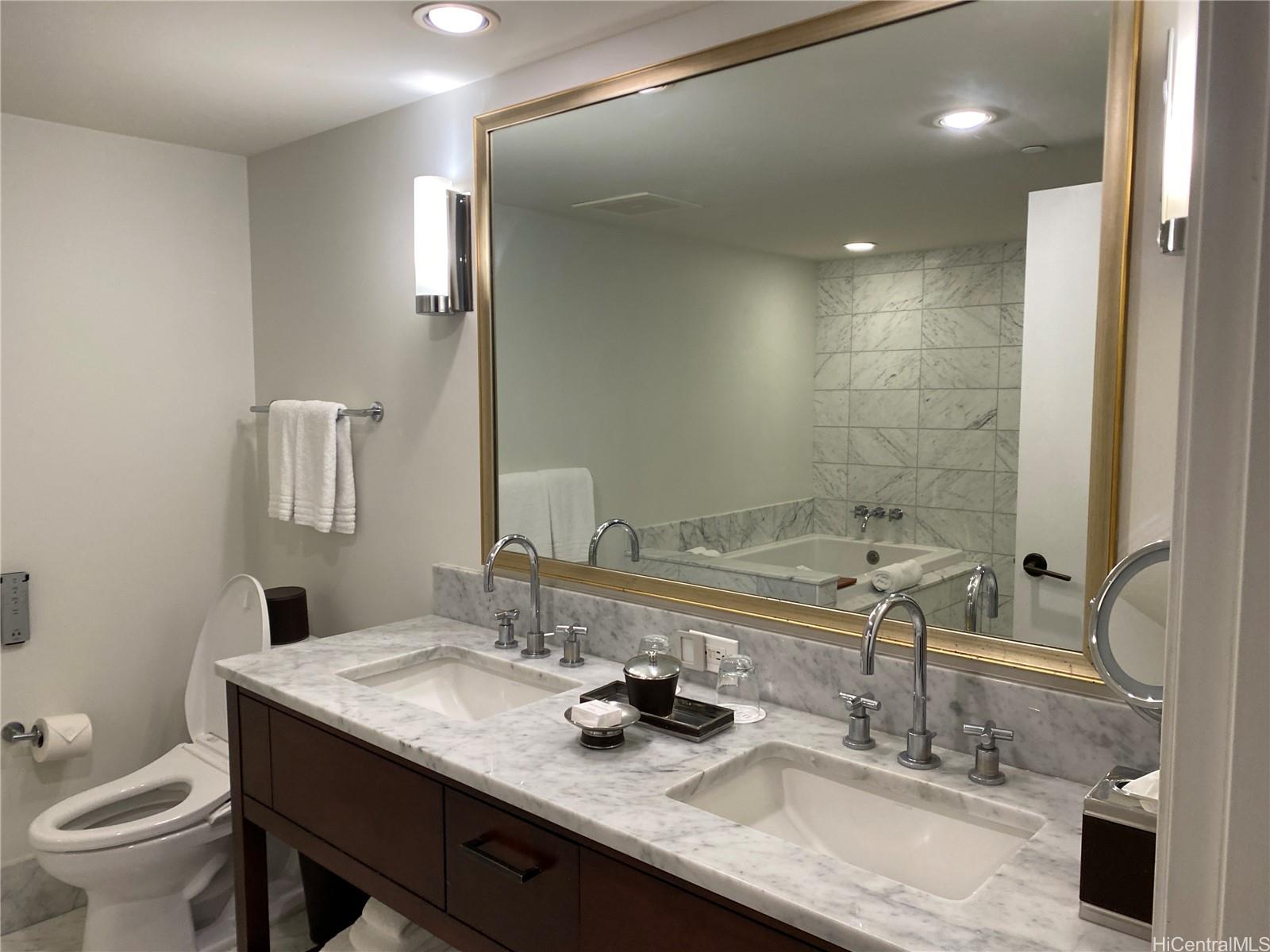 223 Saratoga Road, Unit 2220 Honolulu, HI 96815 - Photo 10 of 15 a bathroom with a granite countertop sink a toilet and a mirror