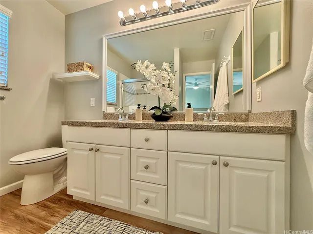 a bathroom with a granite countertop sink vanity mirror and toilet