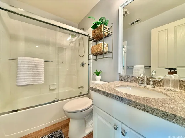 a bathroom with a granite countertop sink toilet and shower