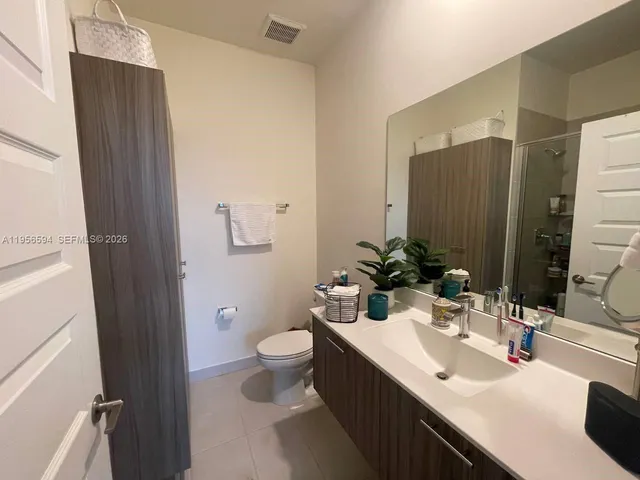a bathroom with double vanity sinks a toilet a mirror and shower