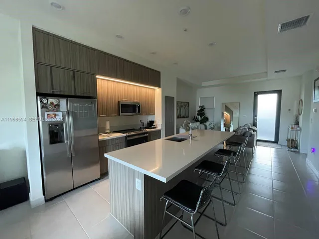 a kitchen with stainless steel appliances a refrigerator a stove a sink a dining table and chairs